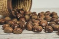 Fresh chestnuts in the basket falling on a white wooden table Royalty Free Stock Photo