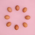 Fresh chicken eggs arrangement in cicrle on pastel pink backgrund. Easter copy space flat lay