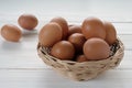 Fresh chicken eggs in the basket on white wooden background