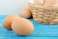 Fresh chicken eggs on blue distressed wooden table.