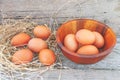 Fresh chicken eggs from the farm are put in a wooden cup and then on the wooden floor Royalty Free Stock Photo