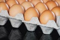 Fresh chicken eggs in gray paper tray cardboard package on black mirror table. Royalty Free Stock Photo
