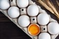 Fresh chicken eggs in a package, raw eggs in a white shell in a box. Top view copy space, wooden background. Broken egg with yolk Royalty Free Stock Photo