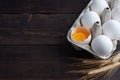 Fresh chicken eggs in a package, raw eggs in a white shell in a box. Top view copy space, wooden background. Broken egg with yolk Royalty Free Stock Photo