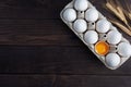 Fresh chicken eggs in a package, raw eggs in a white shell in a box. Top view copy space, wooden background. Broken egg with yolk Royalty Free Stock Photo