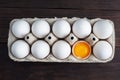 Fresh chicken eggs in a package, raw eggs in a white shell in a box. Top view copy space, wooden background. Broken egg with yolk Royalty Free Stock Photo