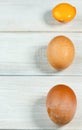 Fresh chicken eggs. Two whole brown chicken eggs and one cracked on a white wooden background Royalty Free Stock Photo