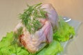 Fresh chicken with lettuce and herbs on a wooden board on the table.