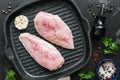 Fresh chicken meat with spices on a grill pan, black stone grunge background. Raw chicken fillet. Top view, flat lay. Royalty Free Stock Photo