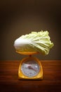 Fresh Chinese cabbage vegetable on kitchen scales  on dark background Royalty Free Stock Photo