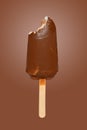 a fresh chocolate outer popsicle with a bite on brown background