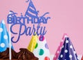 Fresh cholocate delicious birthday cake with maracoons and hats around it on table against pink background. Close up Royalty Free Stock Photo
