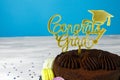 Fresh cholocate delicious  cake with maracoons around it with topper Congrats Grad on the table against blue background. Close up Royalty Free Stock Photo