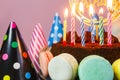 Fresh cholocate delicious cake with maracoons around it with topper Happy birthday and burning candles on the table Royalty Free Stock Photo