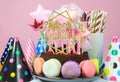 Fresh cholocate delicious cake with maracoons around it with topper Happy birthday on the table against pink background. Royalty Free Stock Photo