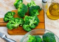 Fresh chopped broccoli with knife, salt and olive oil on wooden board