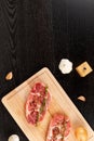 Chopped raw pork steaks with spices, garlic and thyme on a cutting kitchen board on a black wooden table Royalty Free Stock Photo
