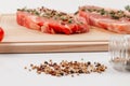 Chopped raw pork steaks with spices and thyme on a cutting kitchen board on a white wooden table Royalty Free Stock Photo