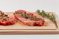 Chopped raw pork steaks with spices and thyme on a cutting kitchen board on a white wooden table Royalty Free Stock Photo