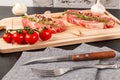 Chopped raw pork steaks with spices, tomatoes and thyme on a cutting kitchen board on a black wooden table. next to a napkin with Royalty Free Stock Photo