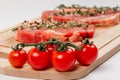 Chopped raw pork steaks with spices, tomatoes and thyme on a cutting kitchen board on a white wooden table Royalty Free Stock Photo