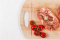 chopped raw pork steaks with spices, tomatoes and thyme on a cutting kitchen board on a white wooden table Royalty Free Stock Photo