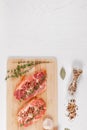 Fresh chopped raw steaks with spices and thyme on a cutting kitchen board on a white wooden table Royalty Free Stock Photo