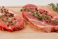 Fresh chopped raw steaks with spices and thyme on a cutting kitchen board on a white wooden table Royalty Free Stock Photo