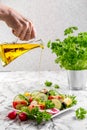 Fresh chopped vegetables in a plate and salad bowl. Hand pours olive oil from a bottle. Healthy eating. Vegetarian food Royalty Free Stock Photo