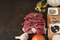 Fresh chunks of raw beef, onions, garlic, olive oil and spices are close-up ready to cook on a dark background Royalty Free Stock Photo