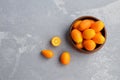 Fresh citrus kumquat fruits in wooden bowl. Healthy vegan food. Top view. Copy space