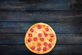 Fresh classic pepperoni pizzai on a dark wooden background. Top view bottom orientation