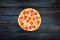 Fresh classic pepperoni pizzai on a dark wooden background. Top view center orientation