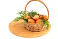 Fresh clean carrots with leaves in a wicker basket on a wooden kitchen board.Isolated on a white background.