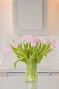 A fresh and clean home office with soft pink tulip flowers in a kitchen for Women`s Day celebration. Airy Scandinavian/Nordic