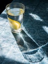 Fresh clean water in a glass with slices of lemon. Lemonade on a beautiful blue tablecloth in the bright morning sun. Living water Royalty Free Stock Photo