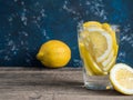 Fresh clean water in a glass with slices of lemon. Lemonade on wooden table and blue background. Living water, healthy drink Royalty Free Stock Photo