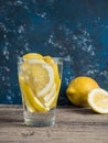 Fresh clean water in a glass with slices of lemon. Lemonade on wooden table and blue background. Living water, healthy drink Royalty Free Stock Photo