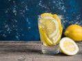 Fresh clean water in a glass with slices of lemon. Lemonade on wooden table and blue background. Living water, healthy drink Royalty Free Stock Photo