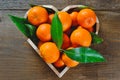 Fresh clementine in a heart shaped box on a wooden background