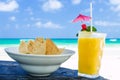 Fresh cocktail with orange juice and nachos on table at tropical exotic Caribbean beach Royalty Free Stock Photo