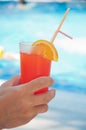 Fresh Cocktail With Orange Slice And Plastic Tube In Man`s Hand On Blue Pool Water Background