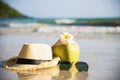 Fresh coconut with hat and sun glasses on clean sand beach with sea wave background