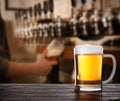 Fresh cold beer on table and bartender in pub, space for text Royalty Free Stock Photo