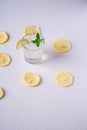Fresh cold clear water drink in glass with ice cubes, lemon slice and mint leaf close to lemon slices Royalty Free Stock Photo