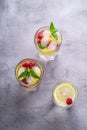 Fresh cold ice water drink with lemon, raspberry fruits and mint leaf in three glass on stone concrete background Royalty Free Stock Photo