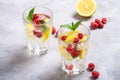 Fresh cold ice water with lemon, raspberry fruits and mint leaf in two faceted glass on stone concrete background Royalty Free Stock Photo