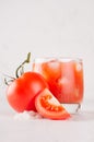 Fresh cold red tomato drink and pulpy tomato with piece, straw, salt on light soft white wood table, closeup. Royalty Free Stock Photo