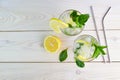 Fresh cold refreshing summer cocktail with lemon, mint and ice. Two glasses with lemonade or mojito on wooden background