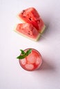 Fresh cold watermelon juice with ice cubes and green mint leaf in glass drink close to two slices of watermelon, top view Royalty Free Stock Photo